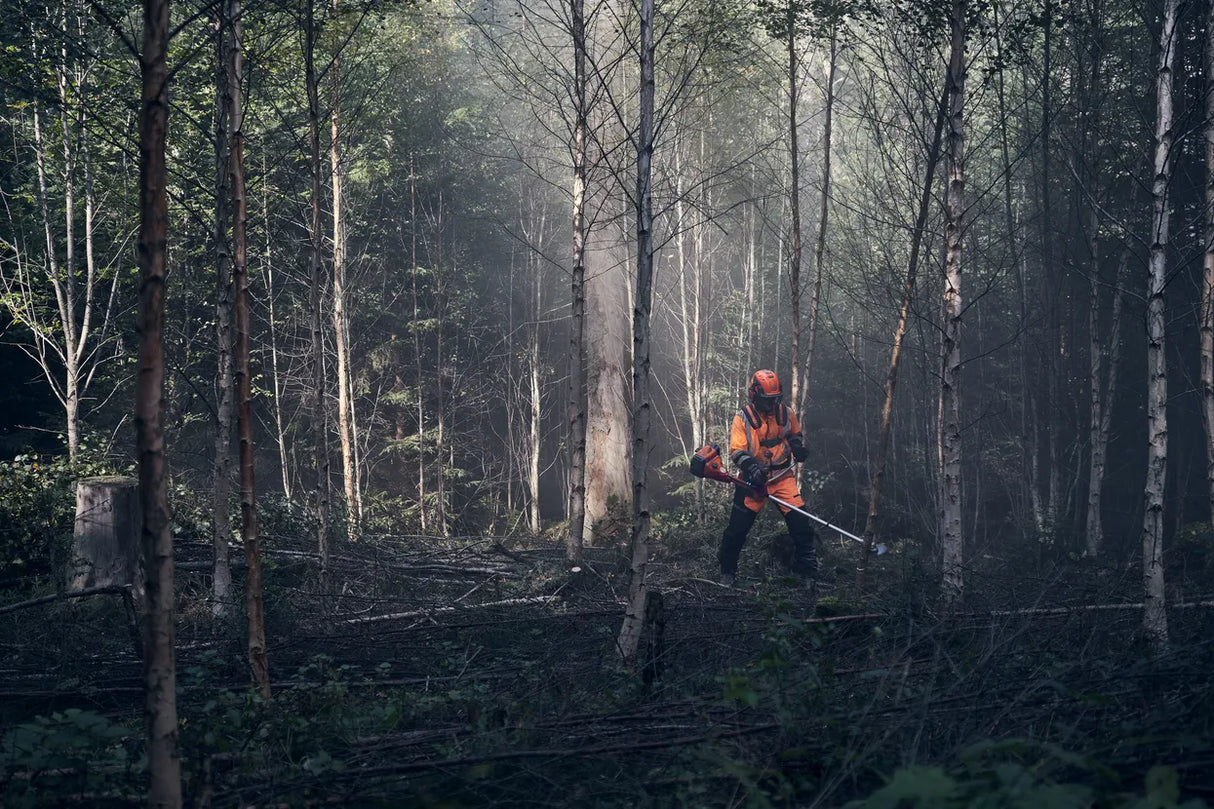 Metsätyöskentelyä Husqvarna 545FXT AutoTune raivaussahalla, jossa käyttäjä käyttää laitetta tiheässä metsikössä.