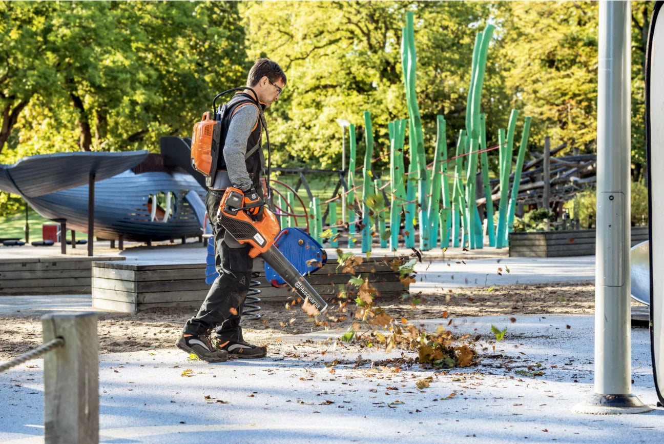 Husqvarna akkupuhallin ulkokäyttöön, tehokas lehtien poistamiseen puutarhasta ja roskien siivoamiseen.