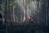 Metsätyöskentelyä Husqvarna 545FXT AutoTune raivaussahalla, jossa käyttäjä käyttää laitetta tiheässä metsikössä.