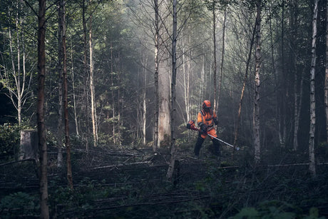 Metsätyöskentelyä Husqvarna 545FXT AutoTune raivaussahalla, jossa käyttäjä käyttää laitetta tiheässä metsikössä.